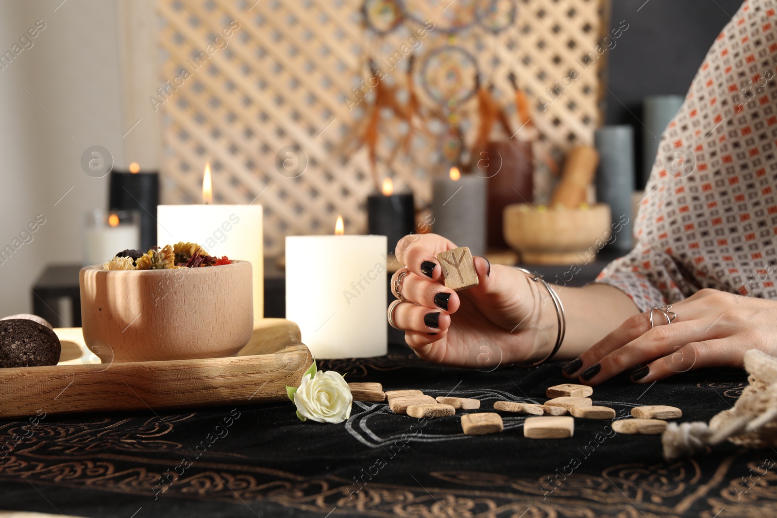 Photo of Woman with wooden runes at divination mat indoors, closeup