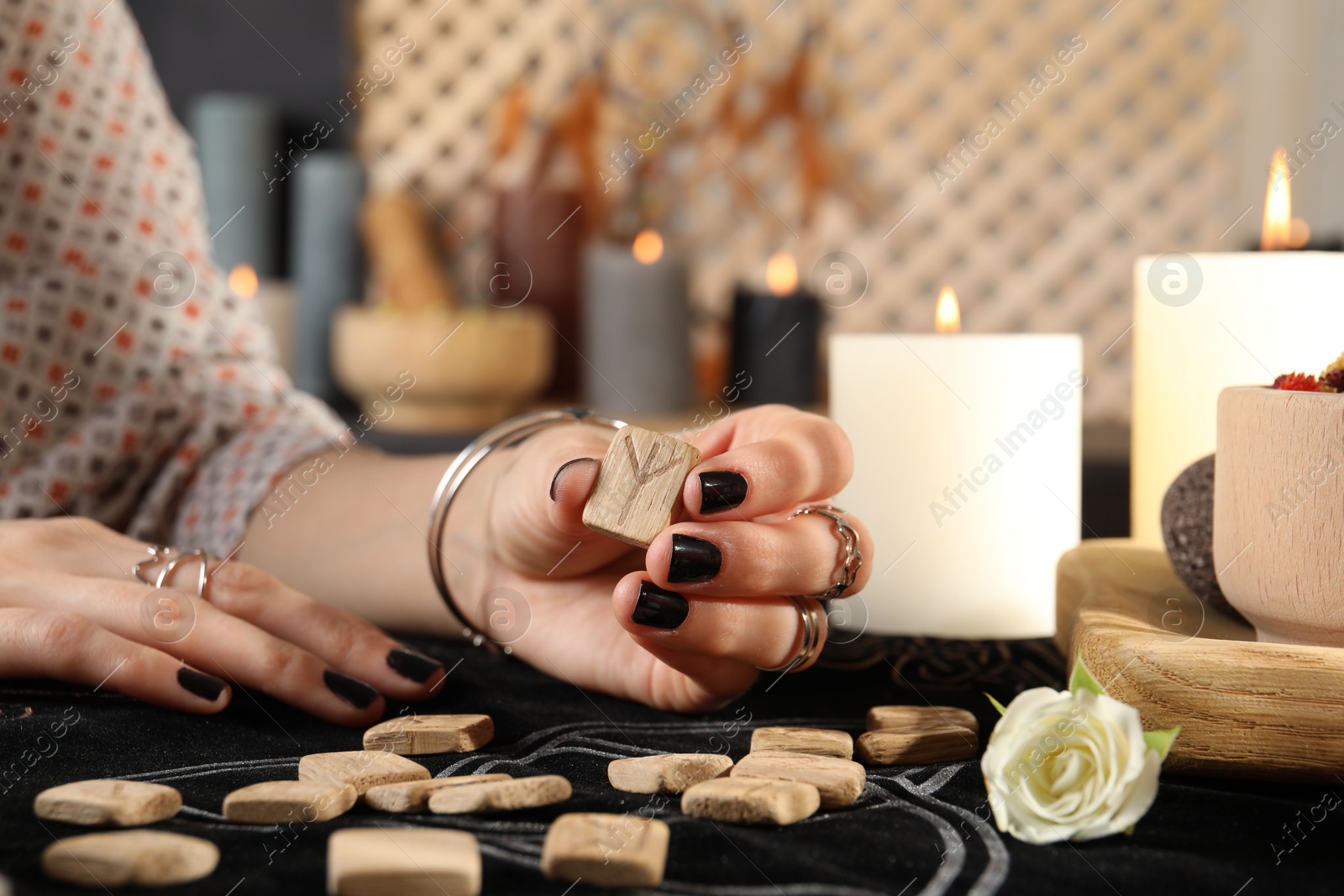 Photo of Woman with wooden runes at divination mat indoors, closeup