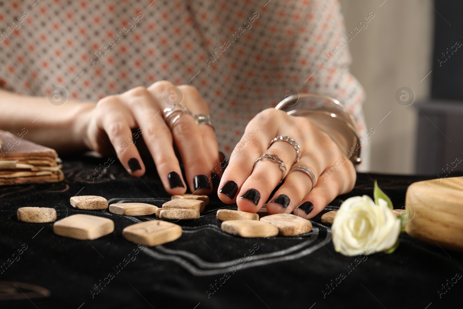 Photo of Woman with wooden runes at divination mat, closeup