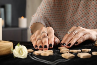 Photo of Woman with wooden runes at divination mat, closeup