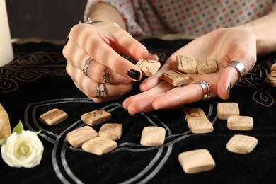 Photo of Woman with wooden runes at divination mat, closeup