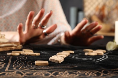 Photo of Woman with wooden runes at divination mat, closeup