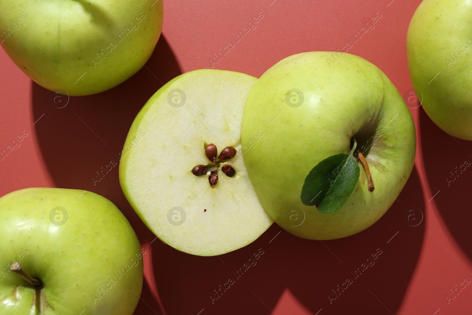 Photo of Whole and cut apples on red background, flat lay