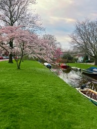 Photo of Picturesque view of canal with moored boats and blossoming trees in spring