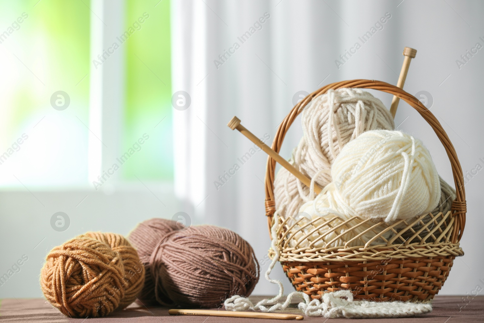 Photo of Skeins of soft yarn and knitting needles on brown fabric indoors