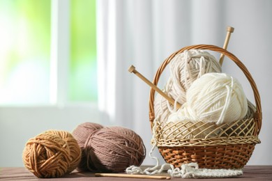 Photo of Skeins of soft yarn and knitting needles on brown fabric indoors