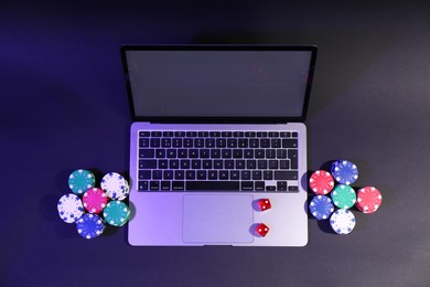 Online poker. Chips, dice and laptop on dark table, above view