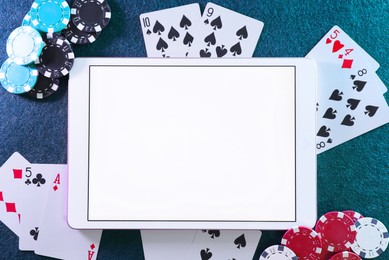 Online poker. Playing cards, chips and tablet on green table, top view