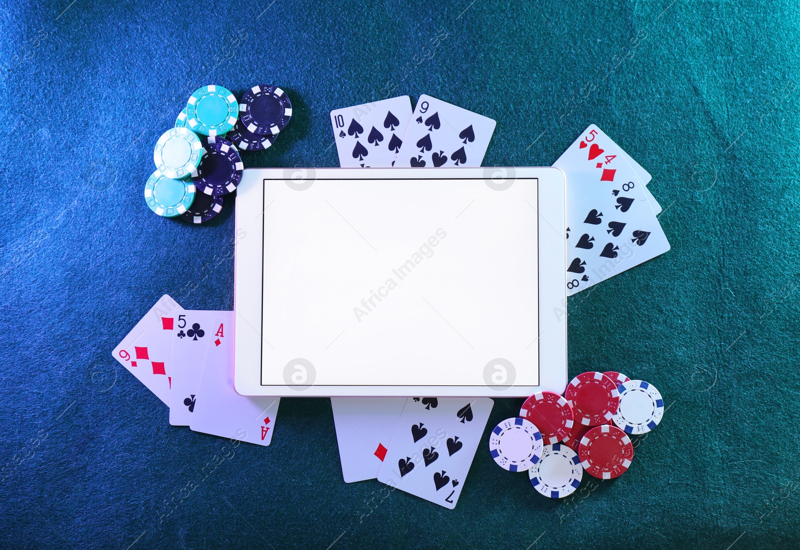 Photo of Online poker. Playing cards, chips and tablet on green table, top view