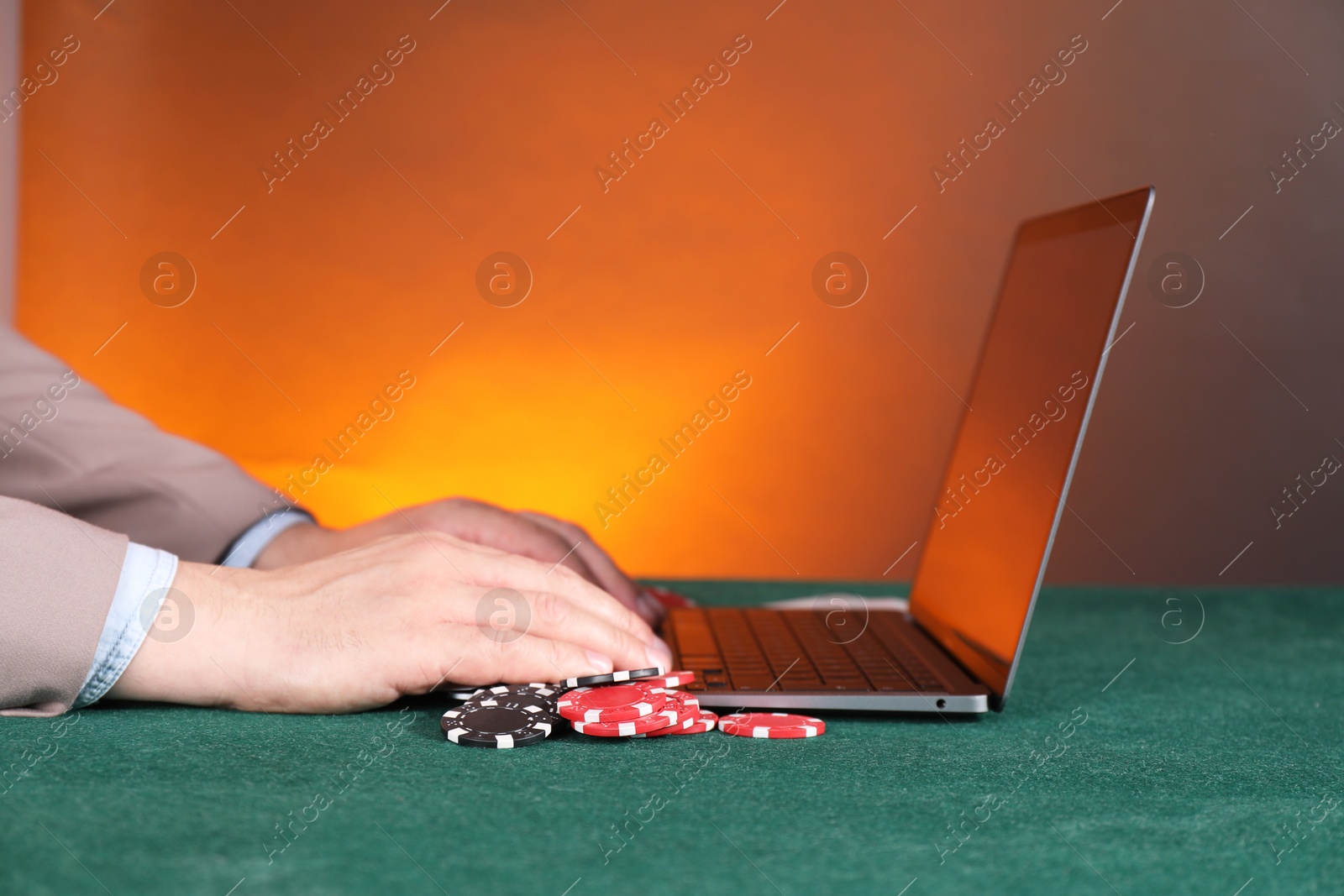 Photo of Online poker. Man using laptop at green table, closeup