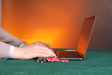 Photo of Online poker. Man using laptop at green table, closeup