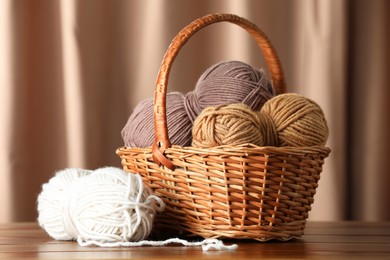 Photo of Knitting material. Wicker basket with skeins of soft yarn on wooden table