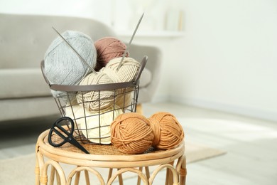 Photo of Skeins of soft yarn, knitting needles and scissors on table indoors, space for text