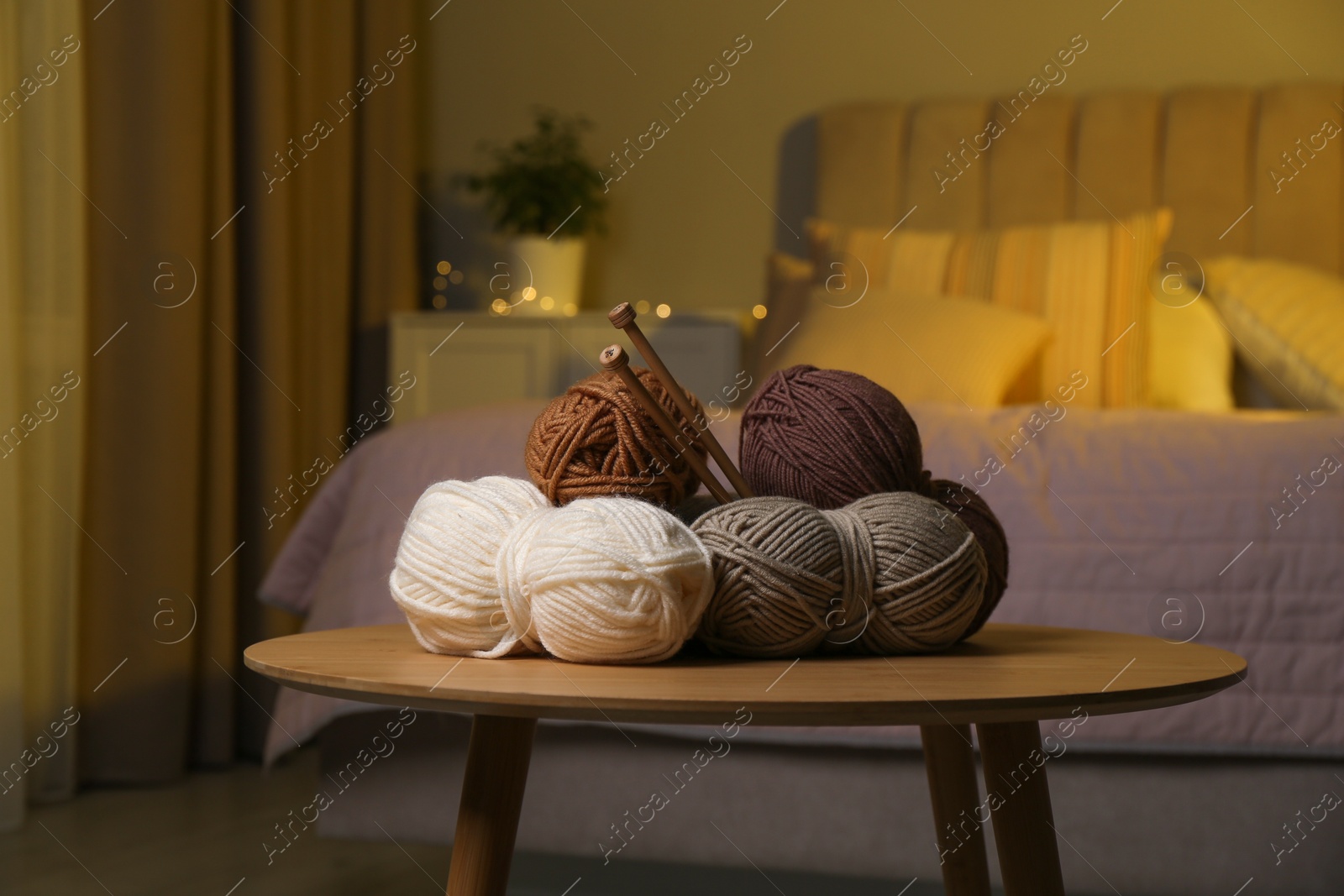 Photo of Skeins of soft yarn and knitting needles on wooden table indoors