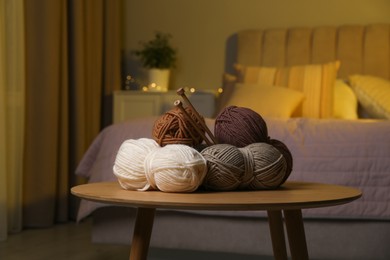 Photo of Skeins of soft yarn and knitting needles on wooden table indoors