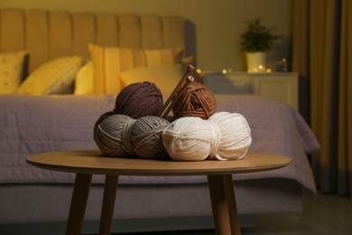 Photo of Skeins of soft yarn and knitting needles on wooden table indoors