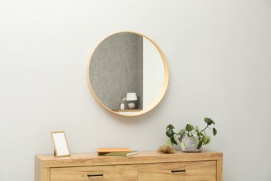 Photo of Round mirror on light grey wall in room. Interior design