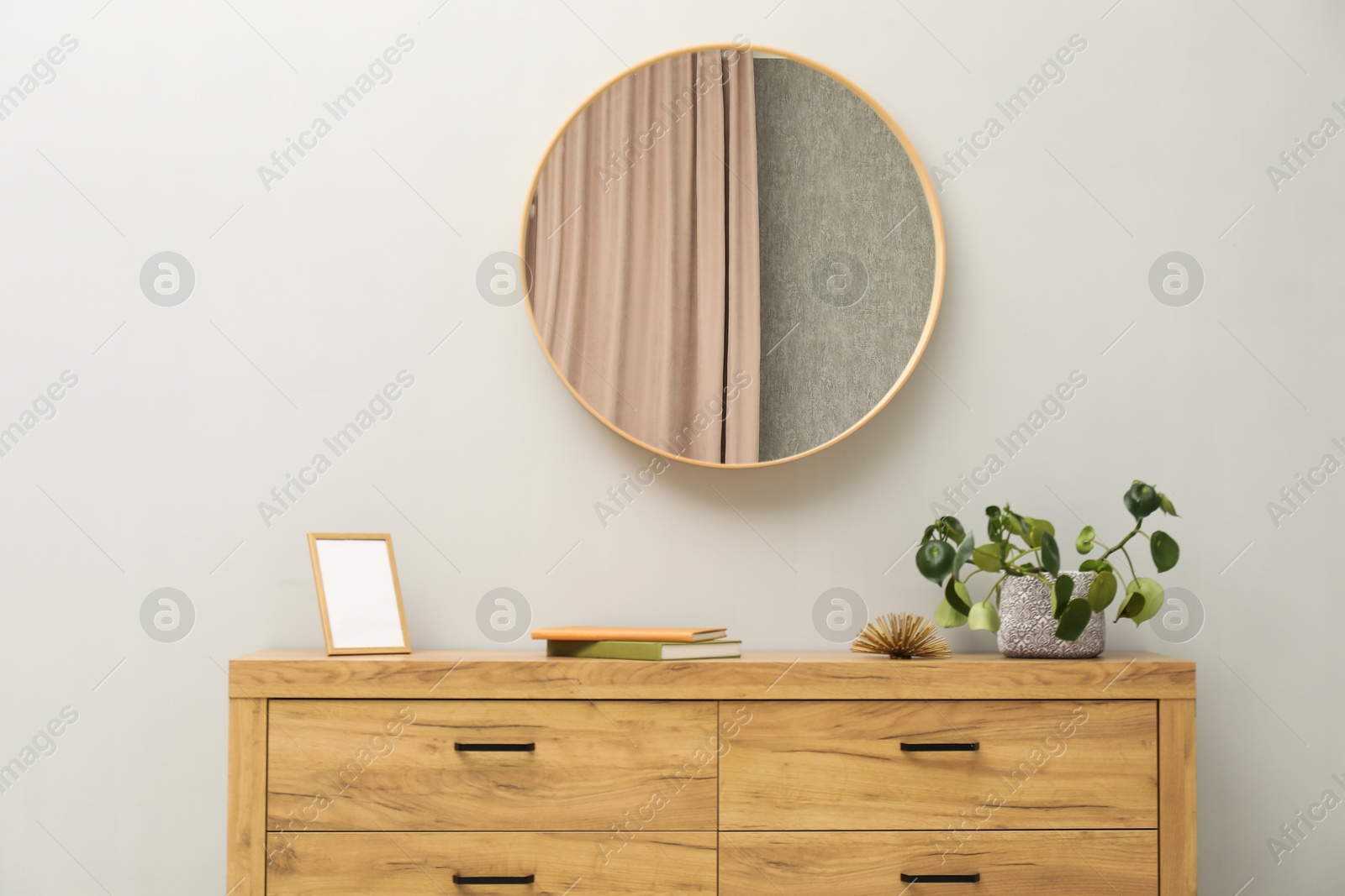 Photo of Round mirror on light grey wall in room. Interior design