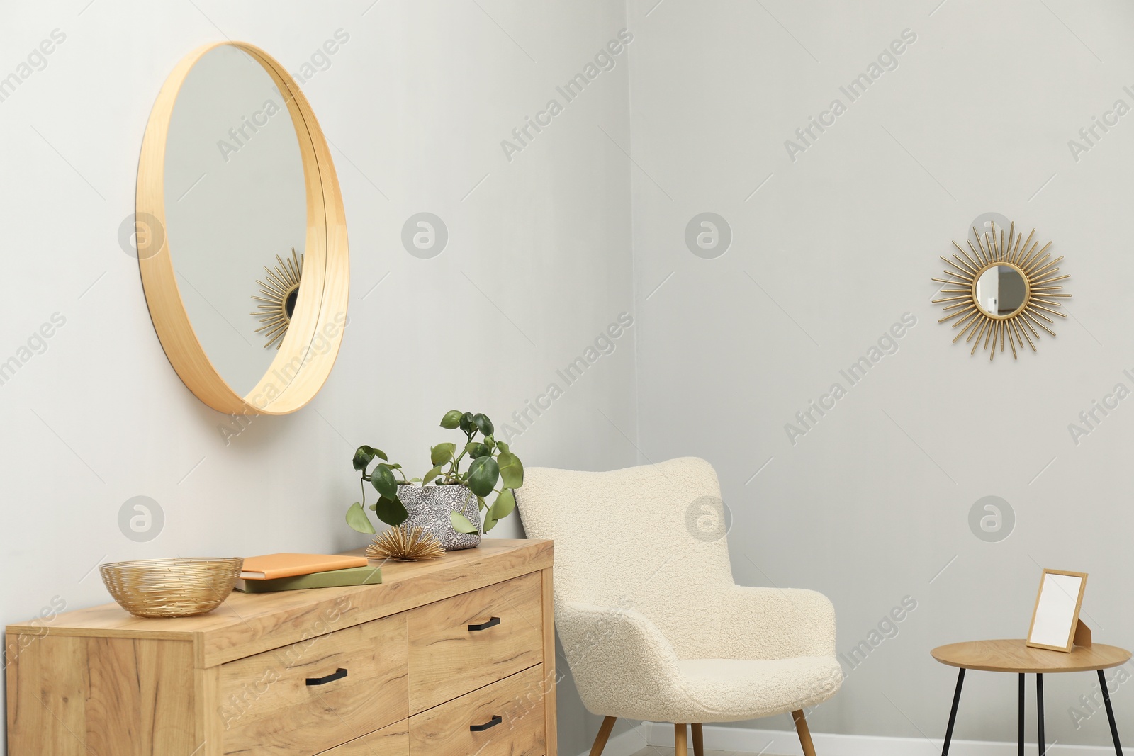 Photo of Round mirror on light grey wall in room. Interior design