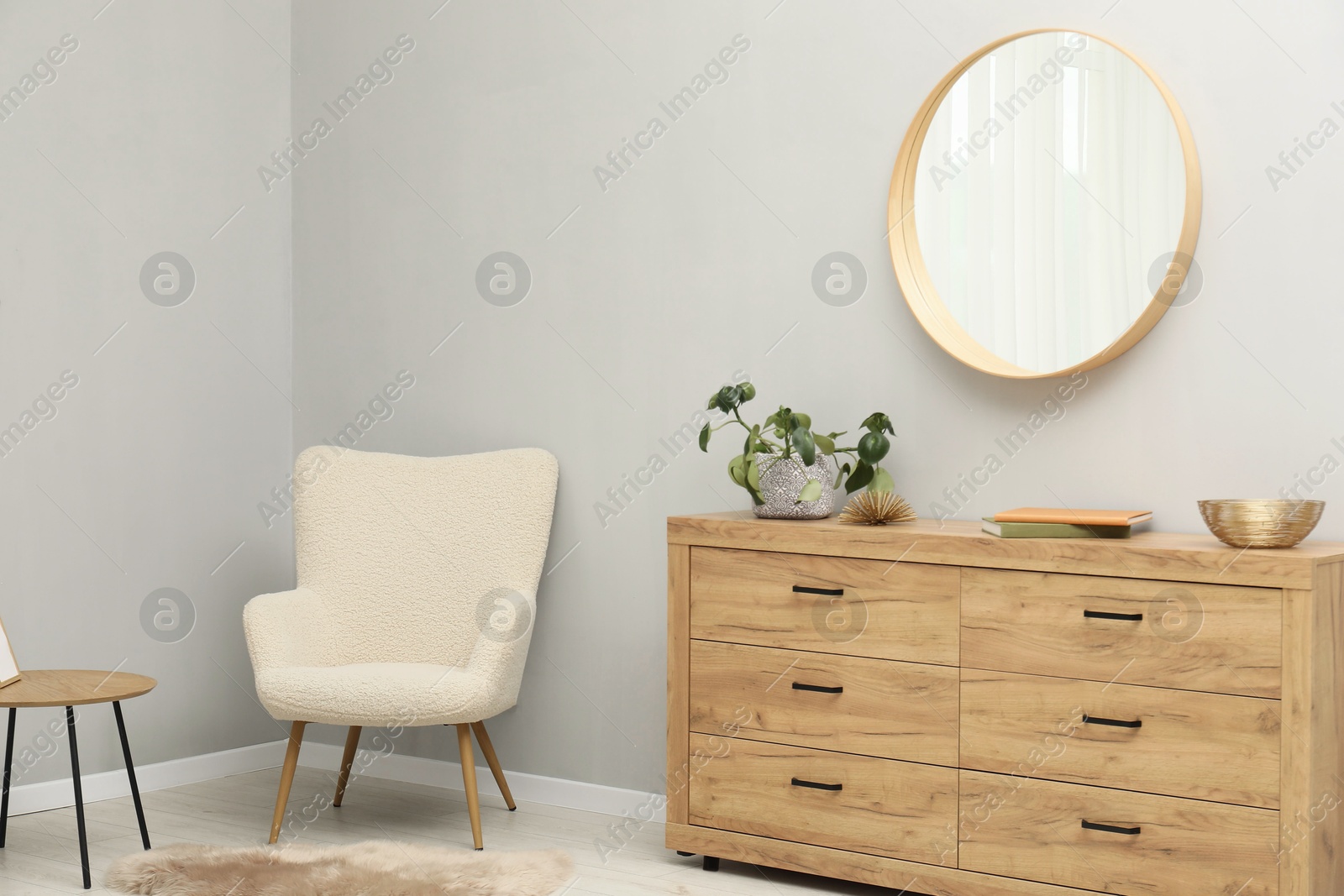 Photo of Round mirror on light grey wall in room. Interior design