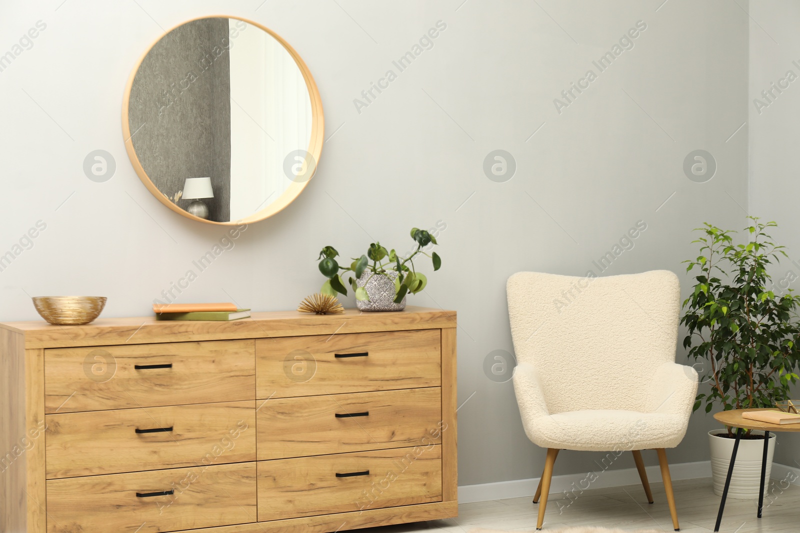 Photo of Round mirror on light grey wall in room. Interior design