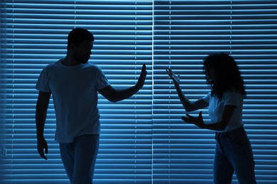 Couple arguing indoors at night. Relationship problems