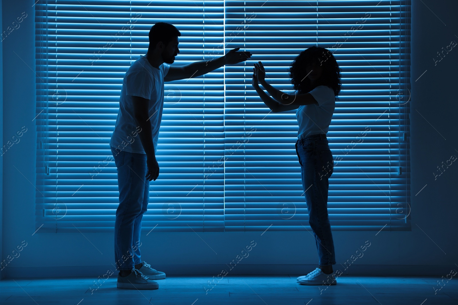 Photo of Emotional couple arguing indoors at night. Relationship problems