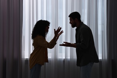 Photo of Emotional couple arguing indoors at night. Relationship problems