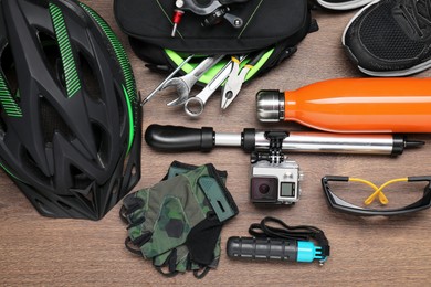 Bicycle accessories and equipment on wooden background, flat lay