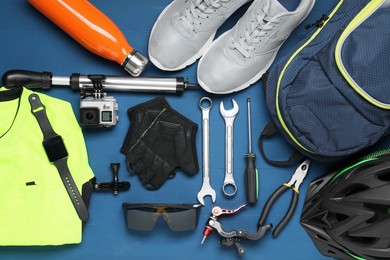 Bicycle accessories and tools on blue wooden background, flat lay