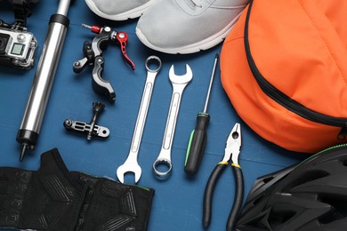 Photo of Bicycle accessories and tools on blue wooden background, flat lay