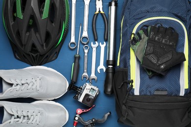 Parts of bicycle, accessories and tools on blue wooden background, flat lay