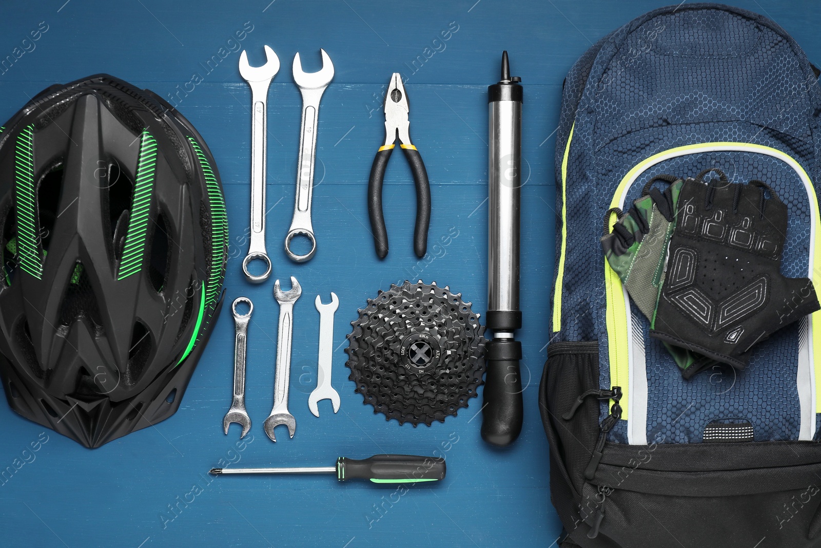 Photo of Parts of bicycle, accessories and tools on blue wooden background, flat lay