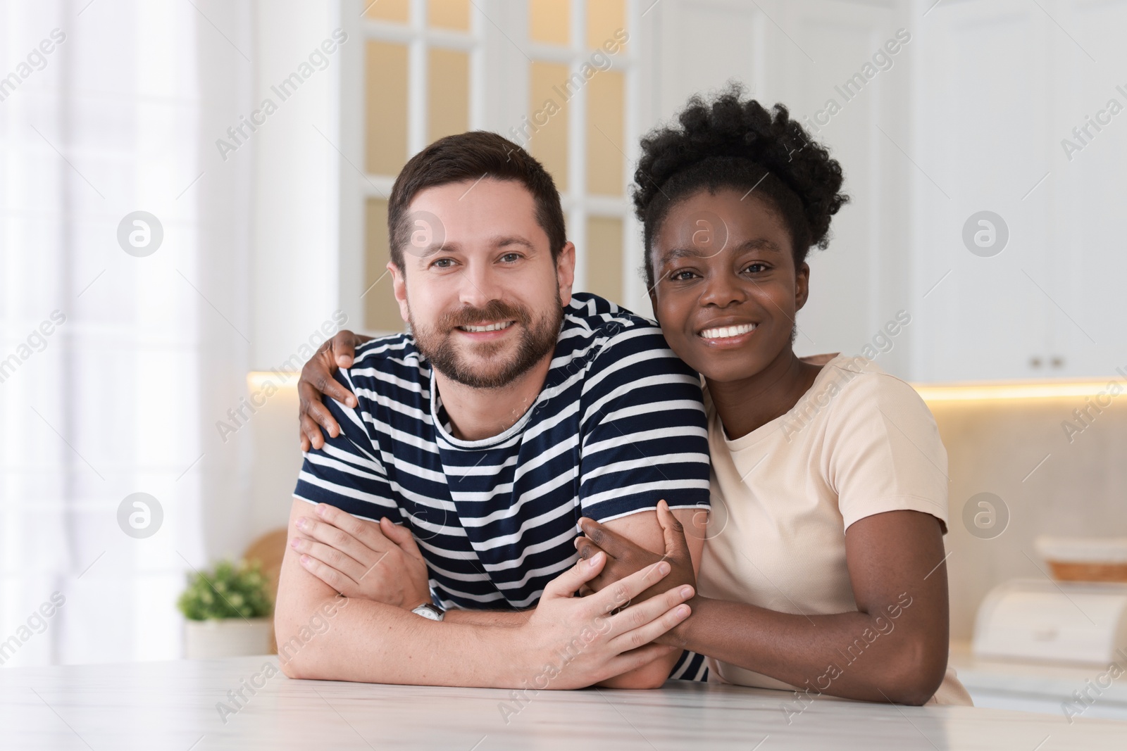 Photo of International relationships. Portrait of lovely couple at white marble table in kitchen