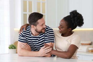 International relationships. Portrait of lovely couple at white marble table in kitchen