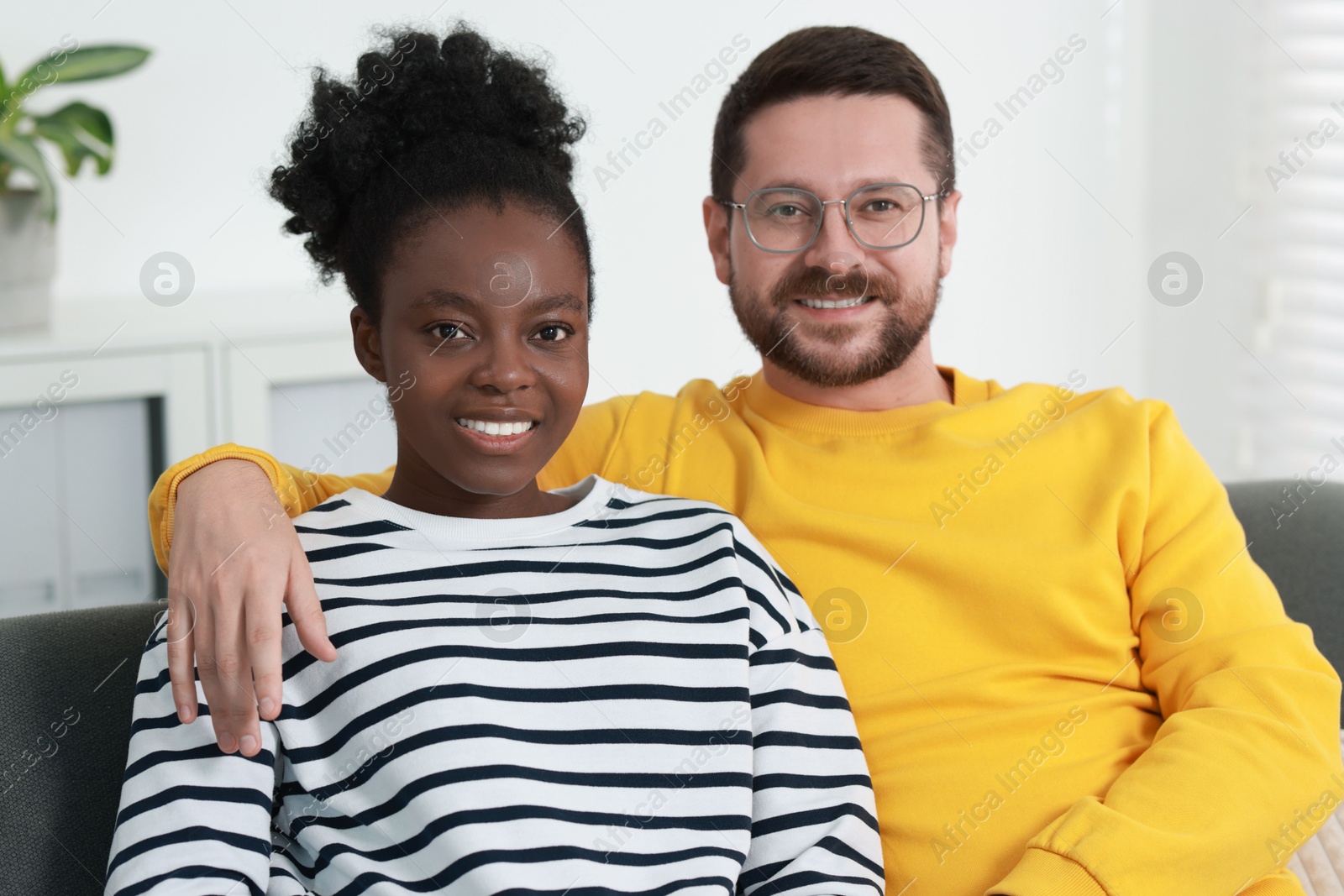 Photo of International relationships. Portrait of lovely couple on sofa at home