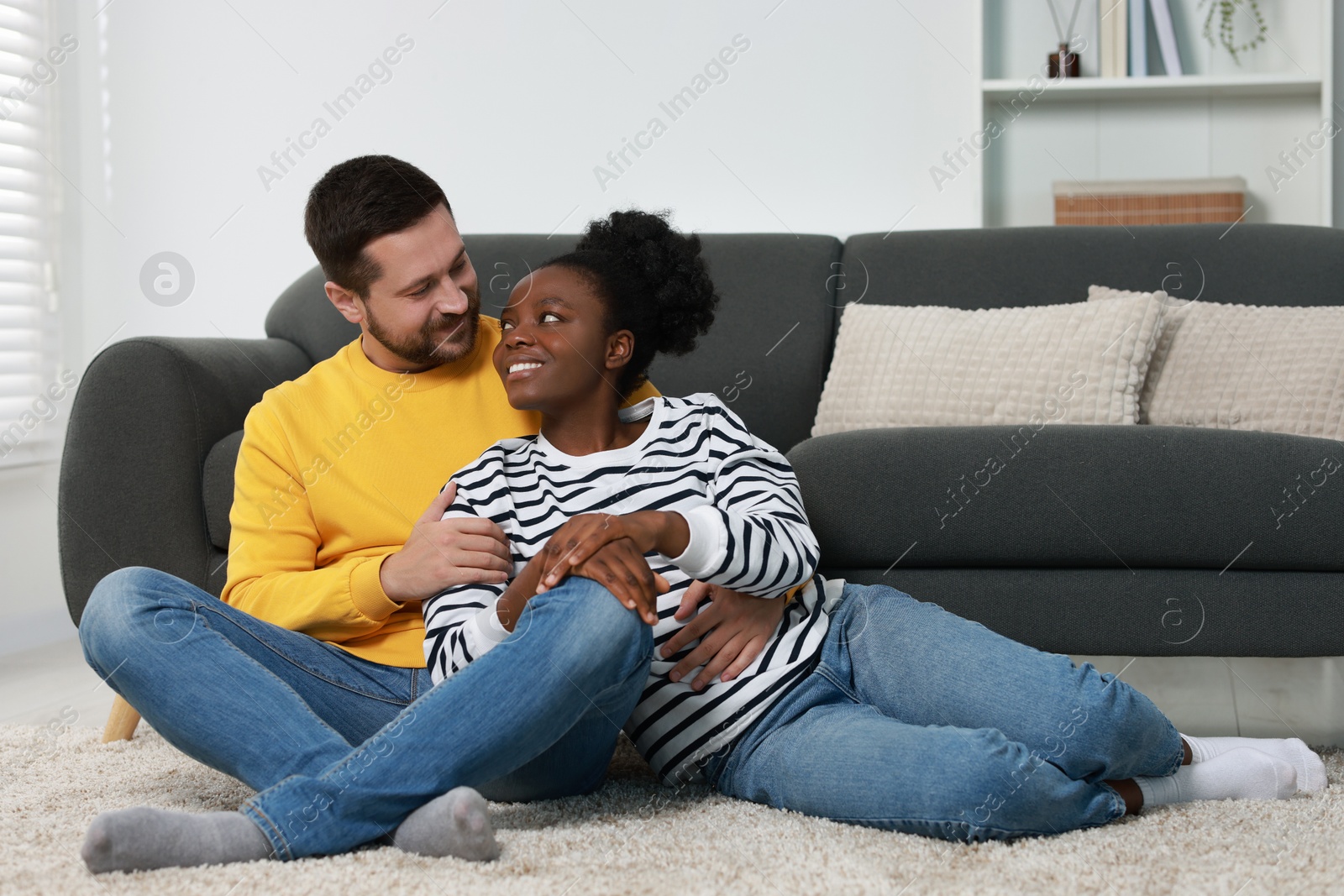 Photo of International relationships. Lovely couple spending time together on floor at home