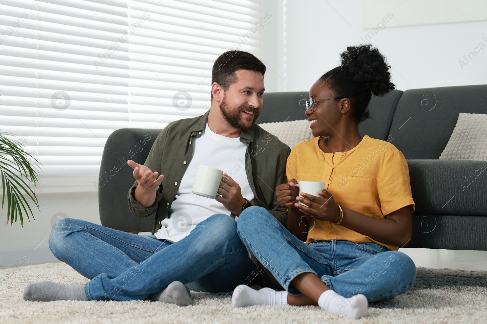 Photo of International relationships. Lovely couple spending time together on floor at home