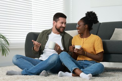 Photo of International relationships. Lovely couple spending time together on floor at home