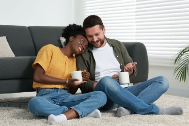 International relationships. Lovely couple enjoying hot drinks on floor at home