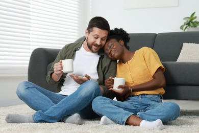 Photo of International relationships. Lovely couple enjoying hot drinks on floor at home