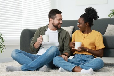 International relationships. Lovely couple enjoying hot drinks on floor at home