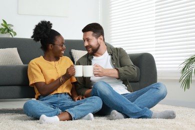 International relationships. Lovely couple enjoying hot drinks on floor at home