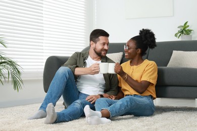 International relationships. Lovely couple enjoying hot drinks on floor at home