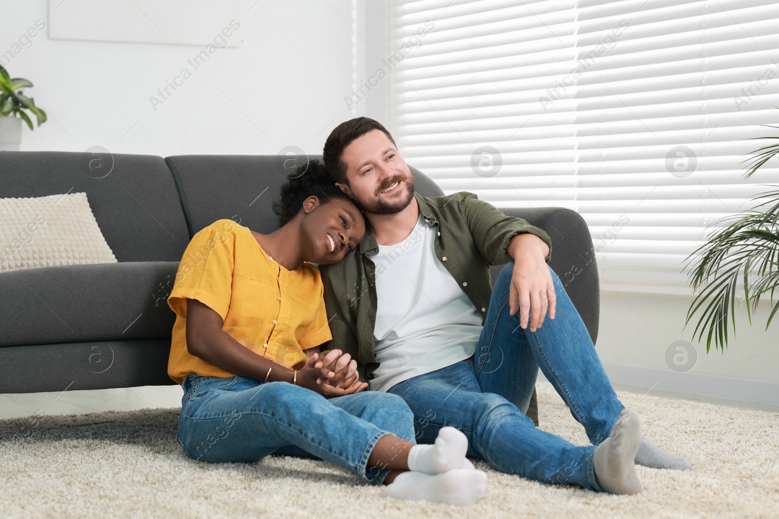 Photo of International relationships. Lovely couple spending time together on floor at home