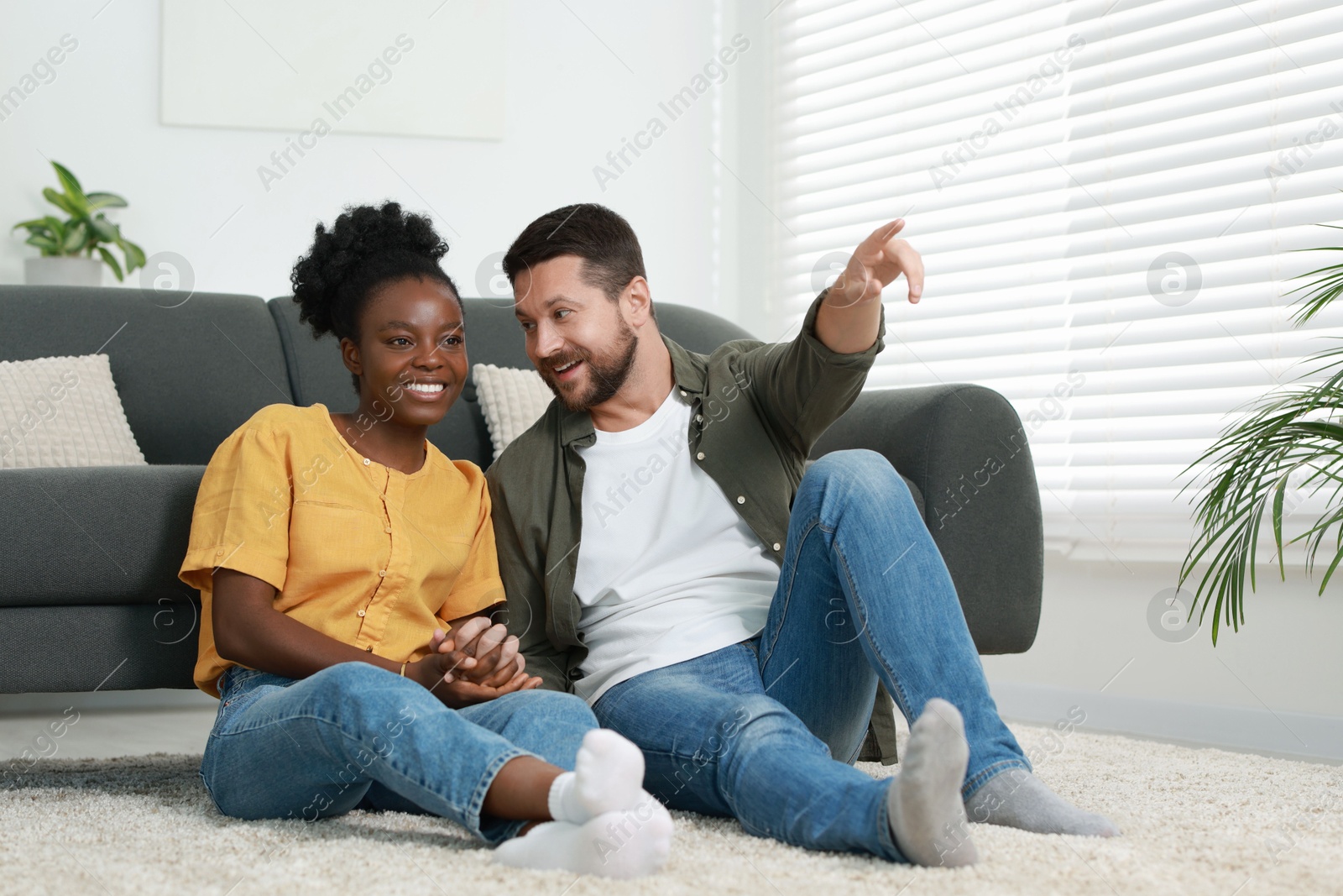 Photo of International relationships. Lovely couple spending time together on floor at home