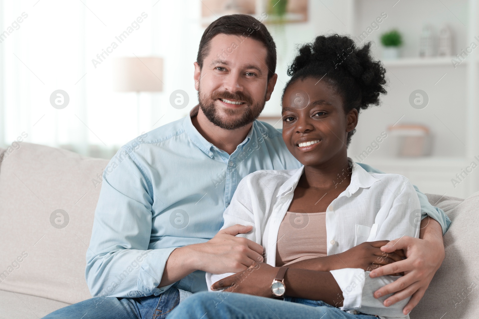 Photo of International relationships. Portrait of lovely couple on sofa at home