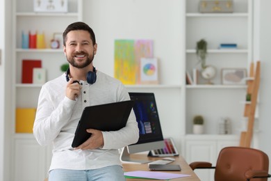 Smiling designer with tablet in office, space for text