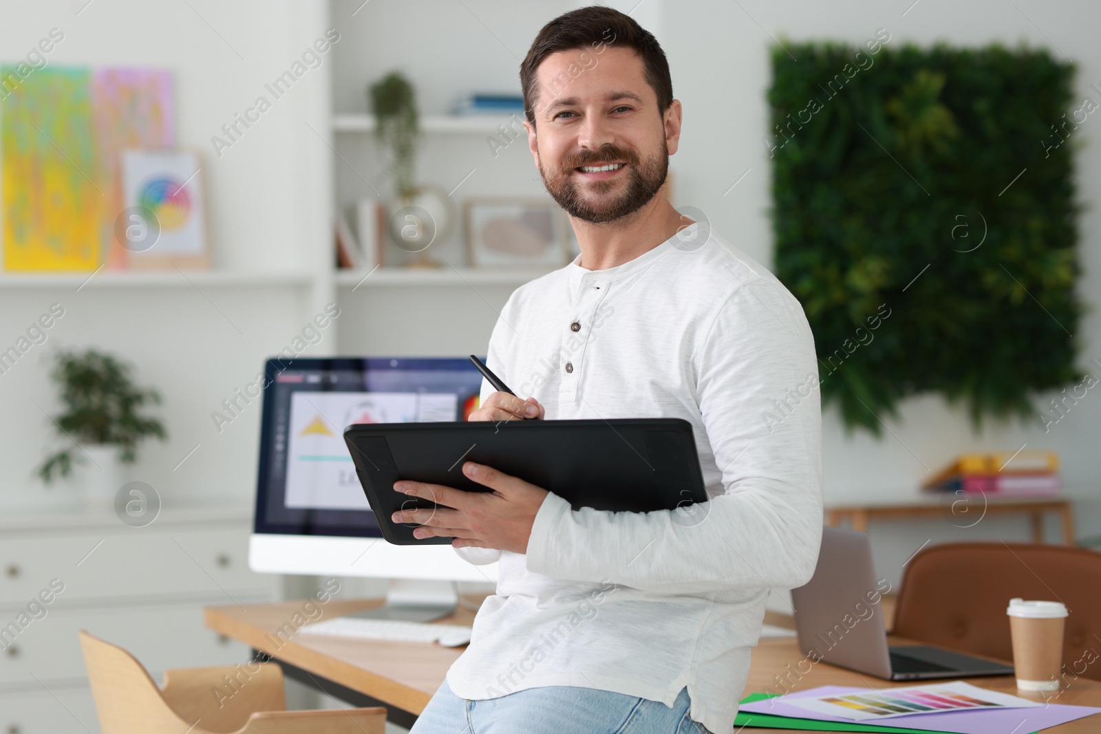 Photo of Smiling designer working with tablet in office