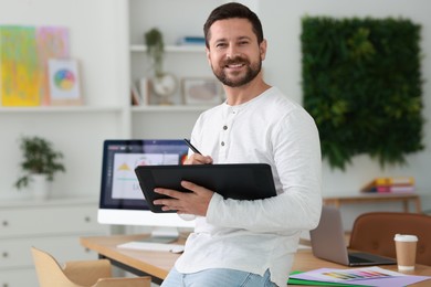 Photo of Smiling designer working with tablet in office